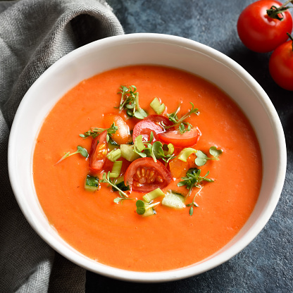 Close up view of gazpacho soup in bowl over dark stone background. Cold tomato soup.