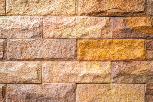 Granite stone tile wall with roughly 3d surface. Background and texture for building texture, selective focus.