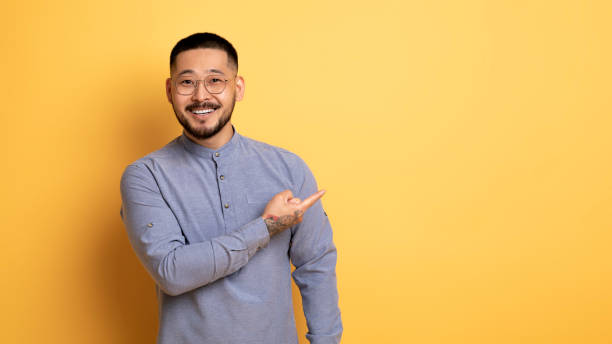 istock Look There. Handsome Asian Man Pointing Aside At Copy Space With Hand 1759879483