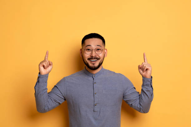 istock Look Up. Cheerful Asian Guy Pointing Fingers Upward At Copy Space 1759880047