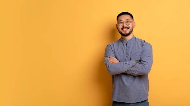 istock Confident young asian man standing with folded arms over yellow background 1759880048
