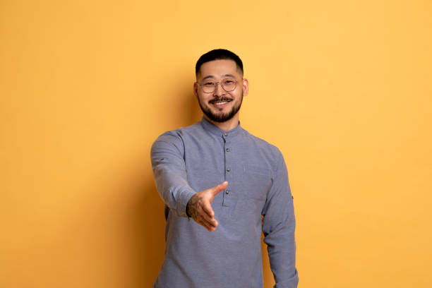 istock Smiling Young Asian Man Extending Hand For Handshake At Camera 1759880356