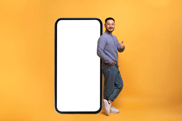 istock Mobile Offer. Excited asian guy leaning on big smartphone with blank screen 1759880651