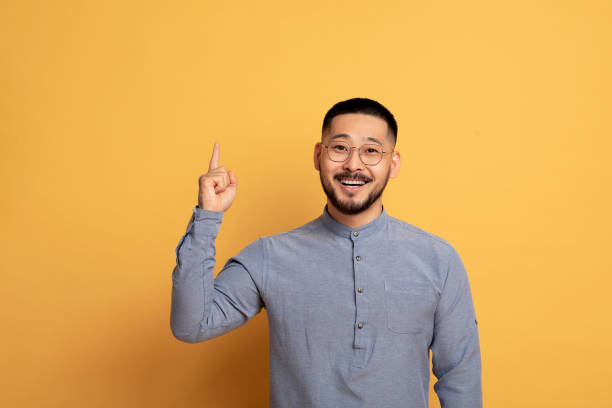 Idea Concept. Excited Asian Man Pointing Finger Up And Looking At Camera