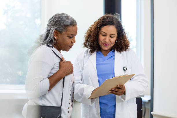 Female healthcare professional talks with her mature female patient about a treatment plan stock photo