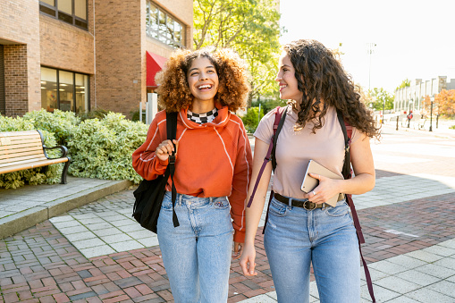 Female friends walking side by side in university campus