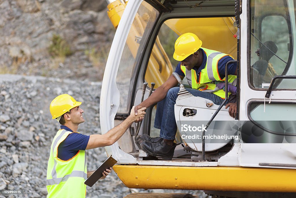 construction manager handshaking with bulldozer operator happy construction manager handshaking with bulldozer operator at construction site Backhoe Stock Photo