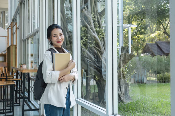istock Attractive young Asian female student stands holding a book to make an appointment with a college friend. 1759905190