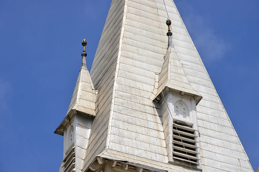 Bell tower of small simple church with cross and birds