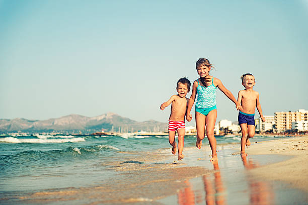 niños corriendo en la playa - child laughing blond hair three people fotografías e imágenes de stock