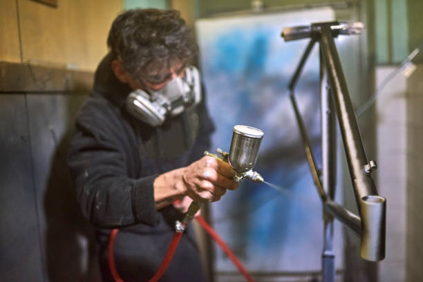 istock Hispanic man spray painting a bicycle frame in his workshop 1759912859