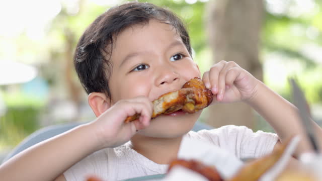 Young boy indulges in a mouthwatering grill chicken wing
