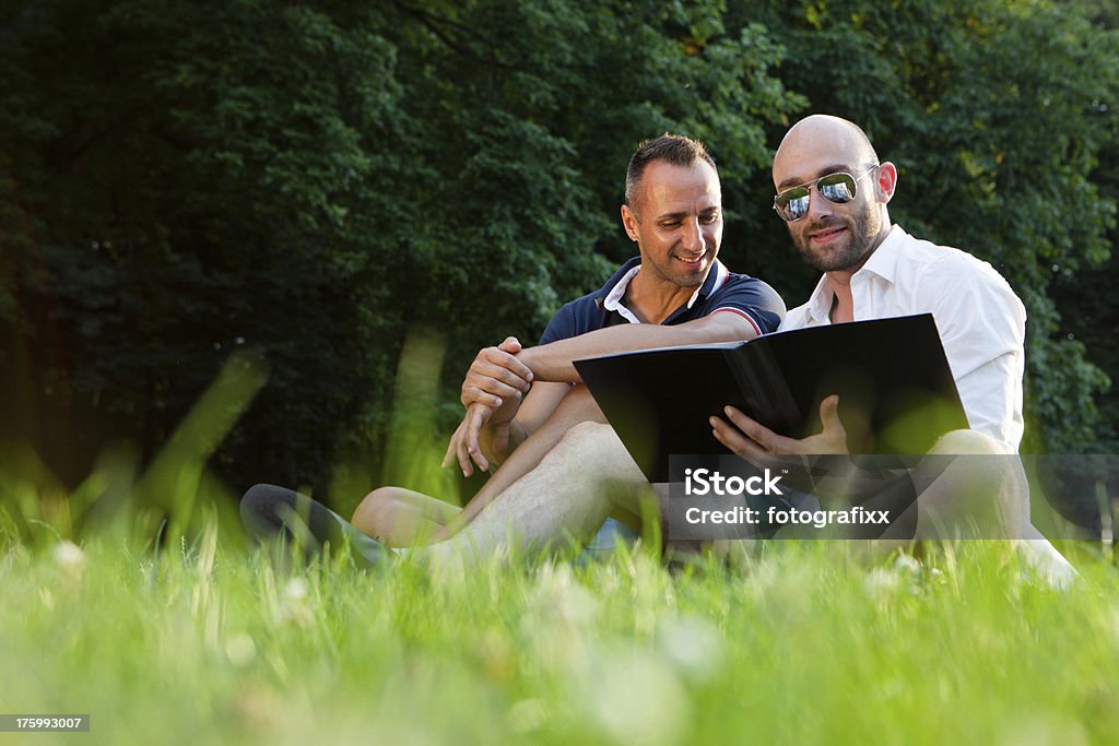 Bella coppia gay rilassarsi in un parco - Foto stock royalty-free di Abbigliamento casual