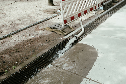 Water flows from the water hose on a construction site into a storm drain