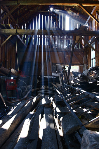 Image of light rays shining through the spaces between barn boards.   