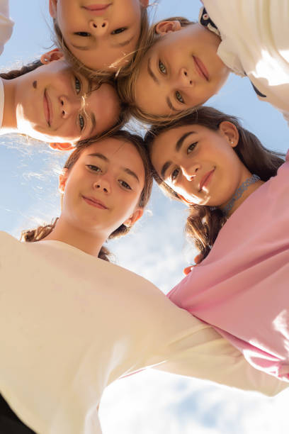 three happy teenage girls dancing and raising arms outdoors