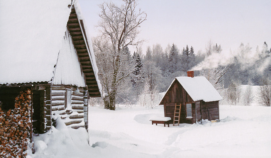 a small wooden house in the forest in winter. round shaped building.