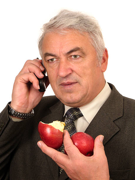 Incredibly Busy Man. III. Thoughtful A white-headed man talking on the phone thoughtfully with a pair of red apples in his hand apple with bite out of it stock pictures, royalty-free photos & images