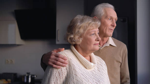 istock An elderly couple hugging and looking out the window, thinking about the future and their retirement 1759957050