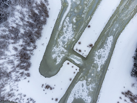 Aerial view of ice on a frozen lake covered with snow in Góry Izerskie, Poland.