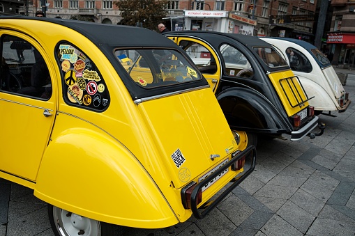 Copenhagen, Denmark – October 07, 2023: Three vintage yellow cars parked side by side, with a street sign in the background