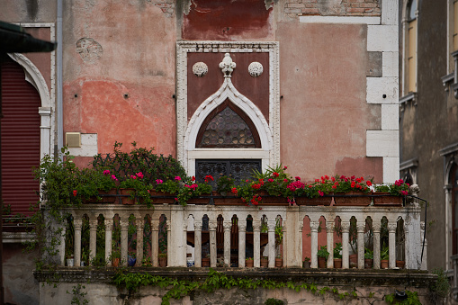 Old Venetian building with a balcony decorated with flowers. Venice - 5 May, 2019