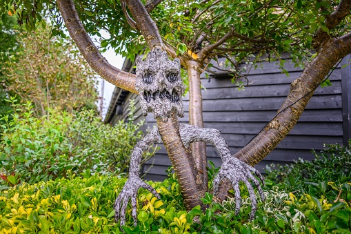 A spooky looking sculpture placed in a garden showcasing lush greenery and vibrant flowers