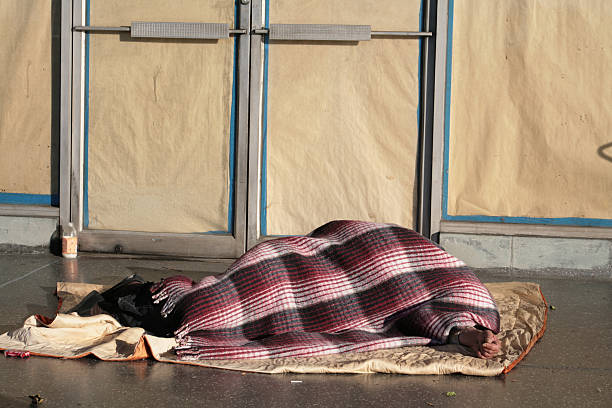 Poor homeless man sleeping on the ground with money tin near him