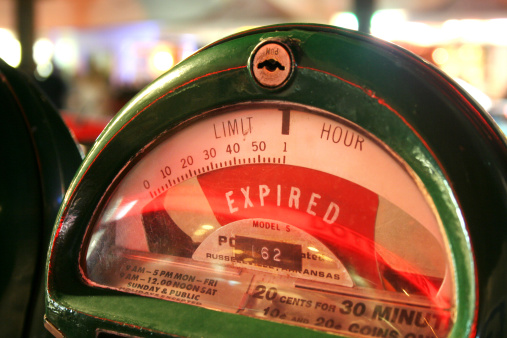 A green parking meter shot at night with red time expired notice.