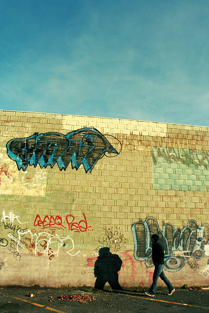 hombre joven contra graffiti - graffiti paintings men walking fotografías e imágenes de stock