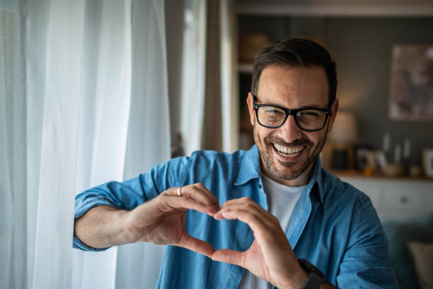 Happy Caucasian man making a heart sign with his hands stock photo