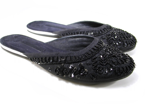 A pair of in fashion black slippers.