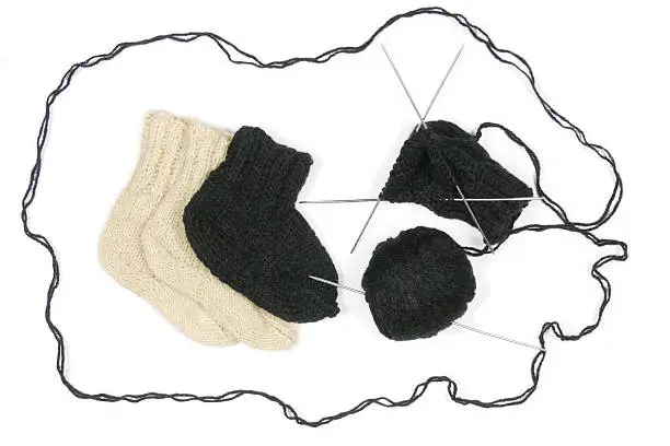 Close up of knitting with spokes and a ball of a wool and two socks. Isolated on white.