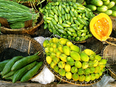 Local fruit market on Bagledesh streets with cucumbers, melons, onions, baby vegetables, in baskets