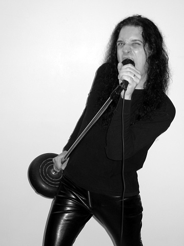 A longhaired male singing and holding the mic and stand.  Taken in black amd white.