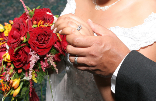 Groom holding bride's hand. Engagement and wedding ring.
