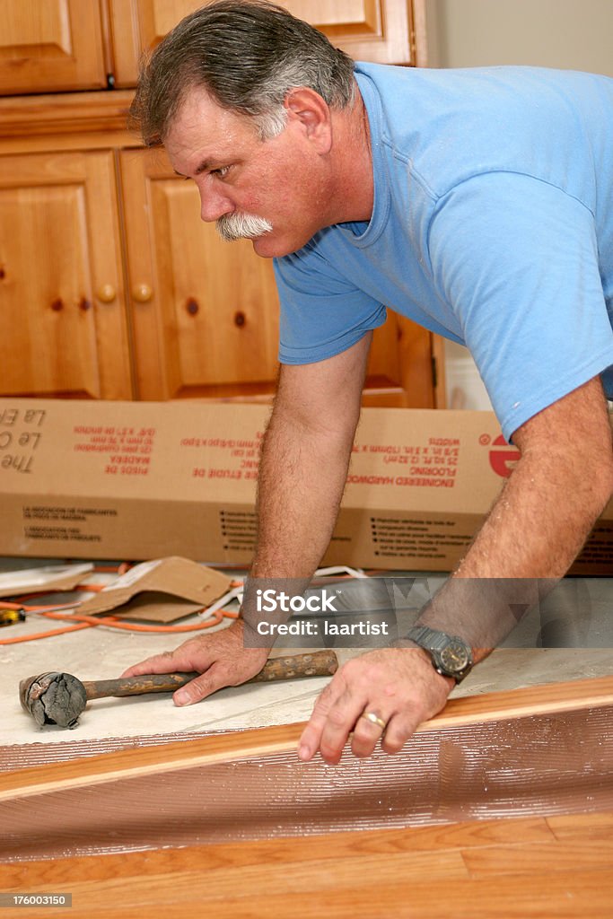 Installing wood floor 8. A worker installs a wood floor. Installing Stock Photo