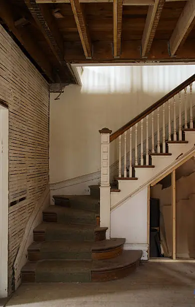 "Old stairs in the house ready for major reconstuction/remodeling. Walls are already stripped of old plaster, some wall panels are missing, walls are old and damaged. This is a perfect ""before and after"" image for house renovation."