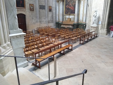 An empty interior of a building featuring wooden stairs and benches: Bayeux Cathedral