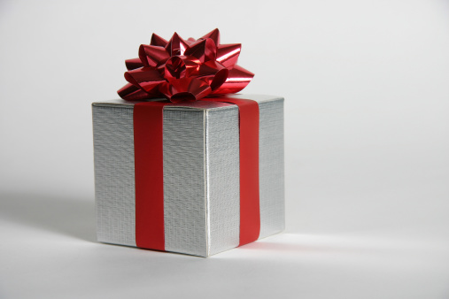 High-quality image of a silver present with bright red bow and ribbon. Light background with plenty of room for your text.