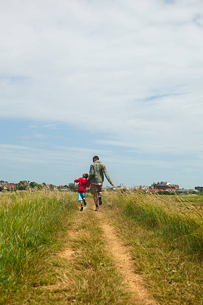 istock father and son happily skipping along country path on journey 176005295