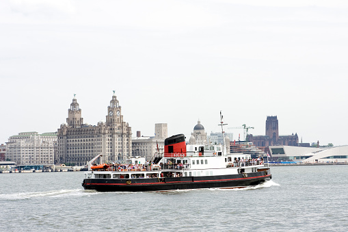The famous Mersey Ferry in Liverpool passing in front of the Royal Liver Building.