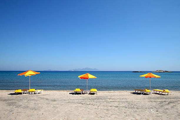 three yellow umbrellas on the beach stock photo