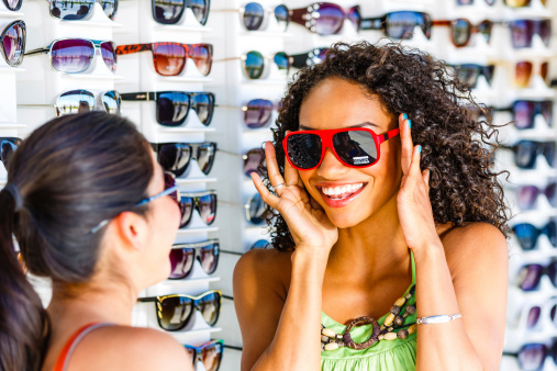 Young women having fun buying sunglasses at Venice beach, LA, USA.