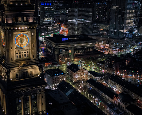 This aerial view captures Boston, MA on a fall night. The regal Clock Tower, overlook a quiet Quincy Market .