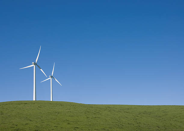 Two wind turbines against clear blue sky stock photo