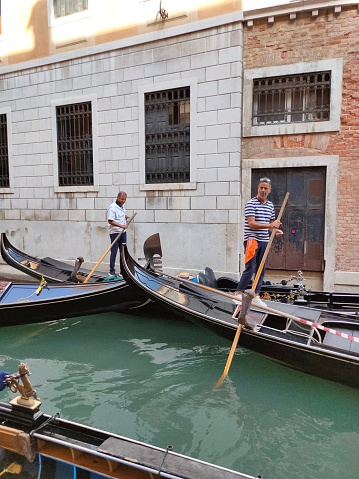 Venice, Italy - October 5, 2023: Gondolier at work in Venice with canal and old buildings at Italy