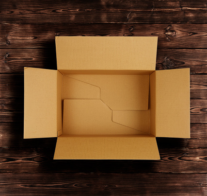 High quality opened rectangular blank empty cardboard brown box isolated on wooden background. Front view angle. Closeup studio shot for postal delivery and suitable for food, cosmetic or medical packaging.