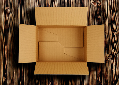 High quality opened rectangular blank empty cardboard brown box isolated on wooden background. Front view angle. Closeup studio shot for postal delivery and suitable for food, cosmetic or medical packaging.