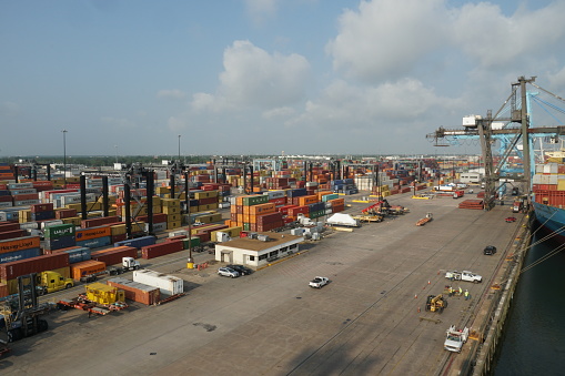 Houston, USA - 06 16 2023: Houston container terminal with green gantry cranes operated by stevedores which are ready for cargo operation. There are behind stowed container from different shippers.